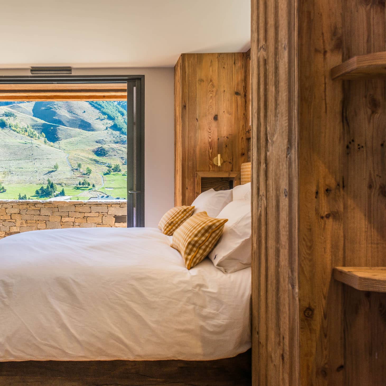 Chambre 1 de 14m² avec lit double 160x200cm, décorée en blanc talque, or brossé et laine à carreaux jaunes. Équipée de TV, balcon avec vue montagne et douche italienne 90x150cm, location chalet 2 Alpes